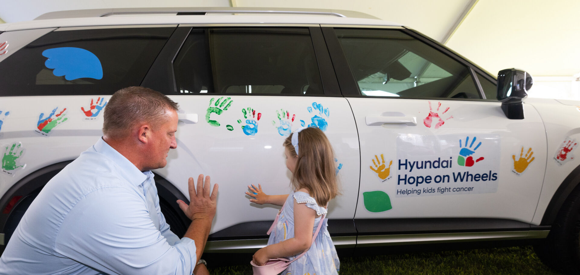 Hyundai hope on wheels ceremony - child puts painted hand print on car