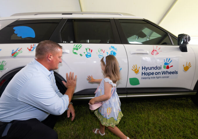 Hyundai hope on wheels ceremony - child puts painted hand print on car