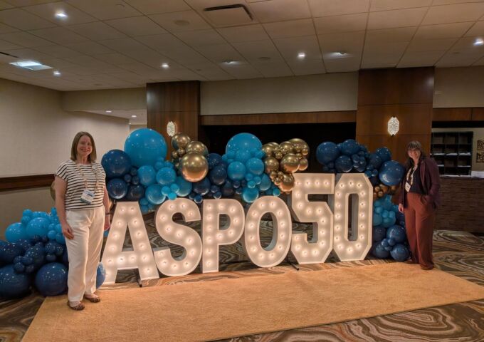 USA Health researchers present cancer prevention strategies at national conference, pose in front of sign