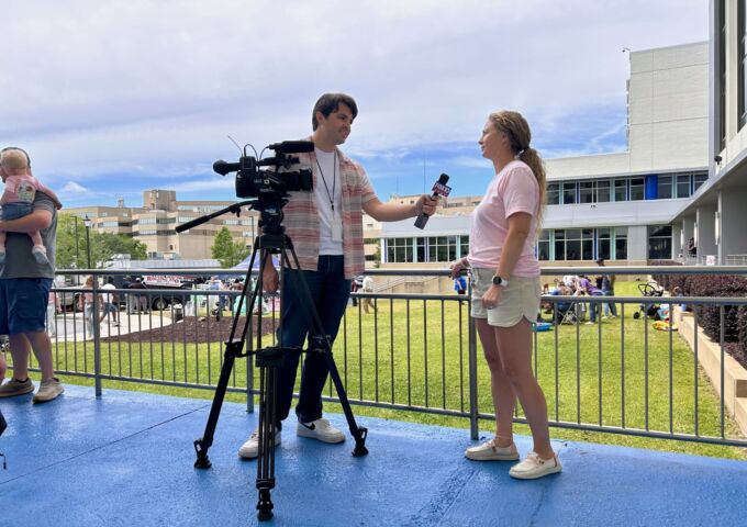 A USA Health employee is interviewed by a television reporter.