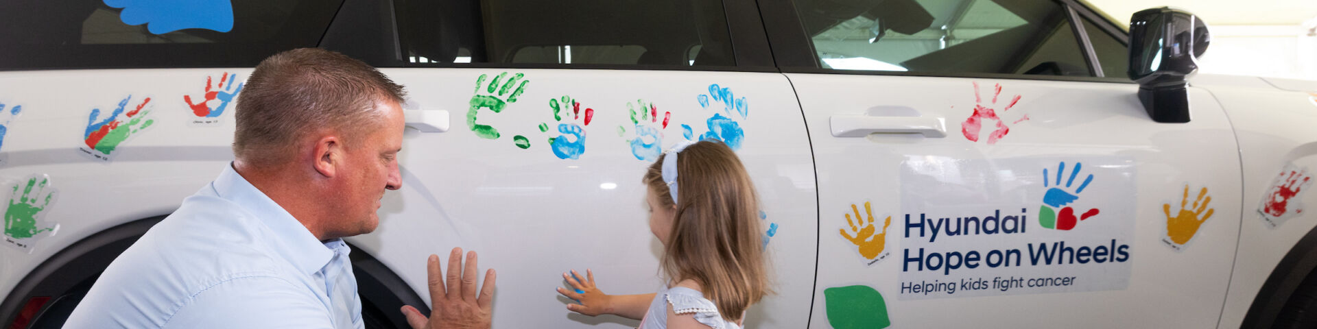 Hyundai hope on wheels ceremony - child puts painted hand print on car