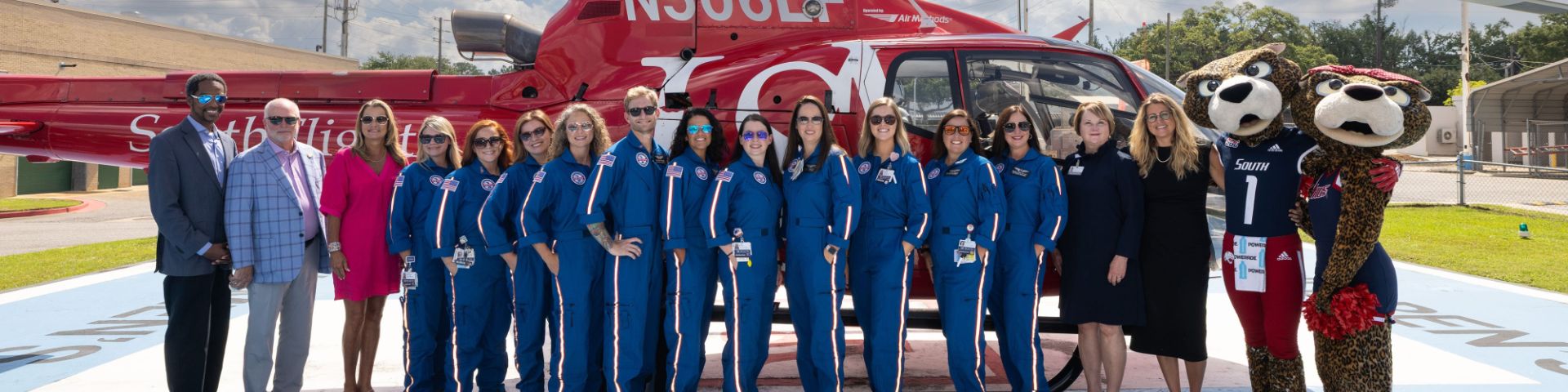 The Cub Crew team at USA Health Children’s & Women’s Hospital poses in front of a helicopter with members of USA leadership.